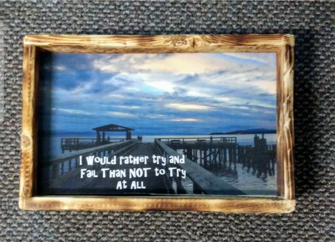 Decoupage sign of a pier at sunset with an inspirational quote in a torched frame