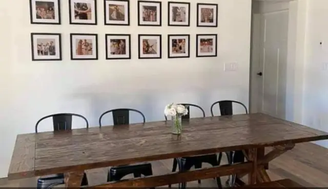Eight-foot handmade farmhouse dining table with trestle base, set with chairs in a dining room