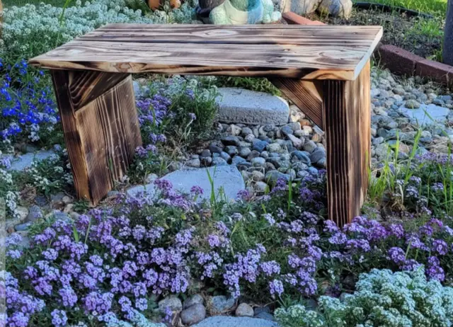 Torched rustic bench in a flower garden