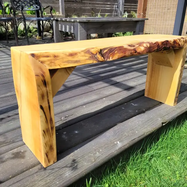 Live-edge wood bench with torched finish on an outdoor deck